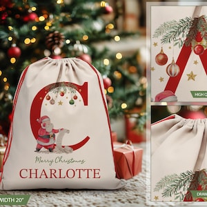 May include: A personalized Christmas gift bag with a red letter C, a Santa Claus illustration, and the text "Merry Christmas CHARLOTTE". The bag is made of natural canvas fabric with a drawstring closure. The bag is 27 inches tall and 20 inches wide.