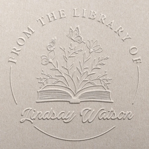 May include: A beige embossed design featuring the text "FROM THE LIBRARY OF" in an arch, with the name "Lindsay Watson" below. The design includes an open book, flowers, and butterflies.