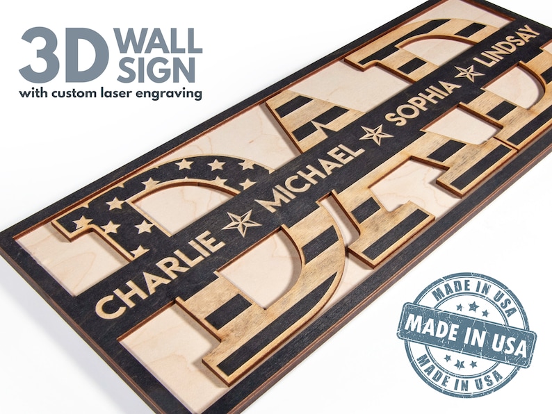 May include: A 3D wooden wall sign spelling "DAD" with an American flag design. The letters are layered and each has a name engraved on it: Charlie, Michael, Sophia, and Lindsay. The sign is framed in black wood and has a "Made in USA" stamp.