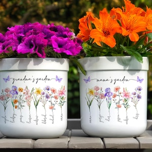 May include: Two white ceramic flower pots with floral designs and the text "grandma's garden" and "mama's garden". Each pot has a row of flowers with names written underneath.