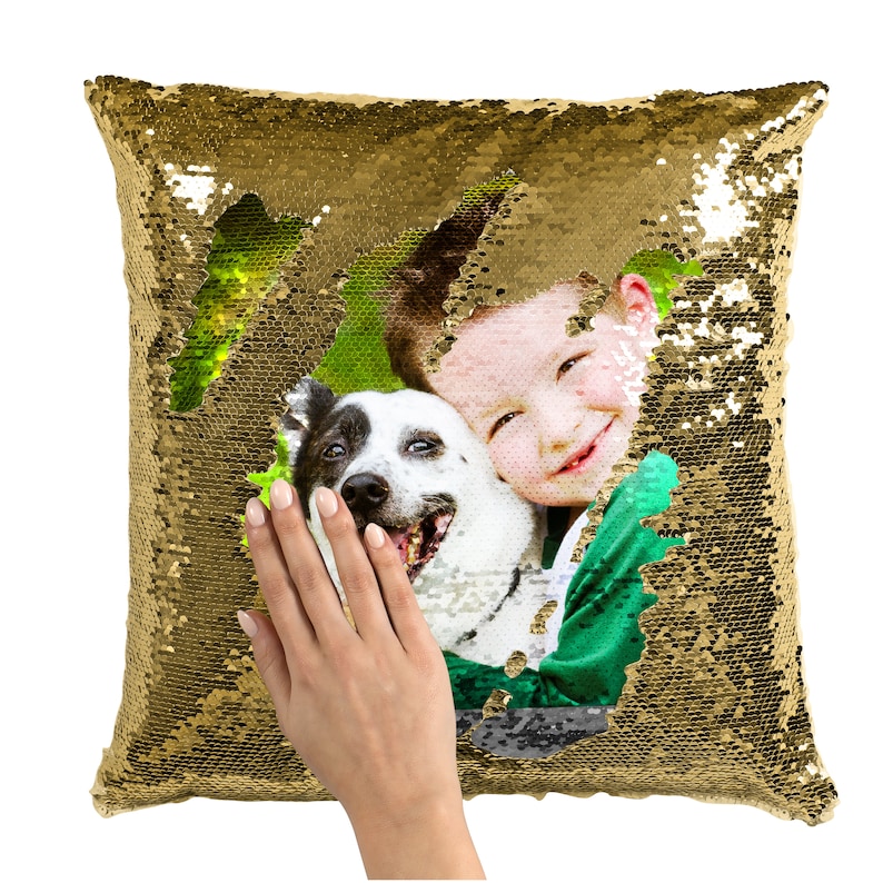 May include: Gold sequin pillow with a photo of a child and a dog peeking through a heart-shaped opening. The photo shows a child smiling and hugging a black and white dog.