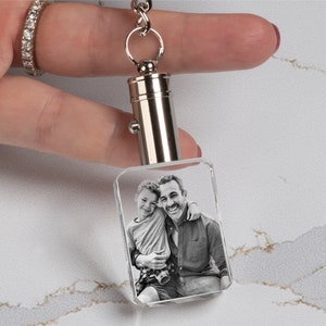 May include: A silver keychain with a clear crystal charm featuring a black and white photo of two people smiling. The photo is engraved inside the crystal.