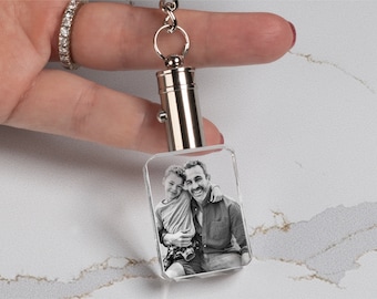 May include: A silver keychain with a clear crystal charm featuring a black and white photo of two people smiling. The photo is engraved inside the crystal.
