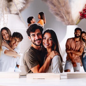 May include: Photo cutouts of couples in various poses, mounted on wooden bases. The images feature smiling people, with a neutral background and decorative elements like dried flowers and berries.