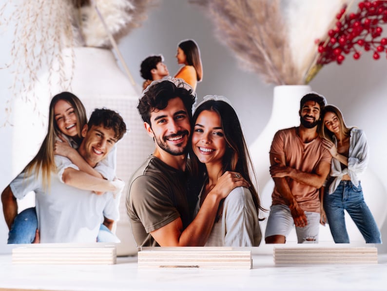 May include: Photo cutouts of couples in various poses, mounted on wooden bases. The images feature smiling people, with a neutral background and decorative elements like dried flowers and berries.