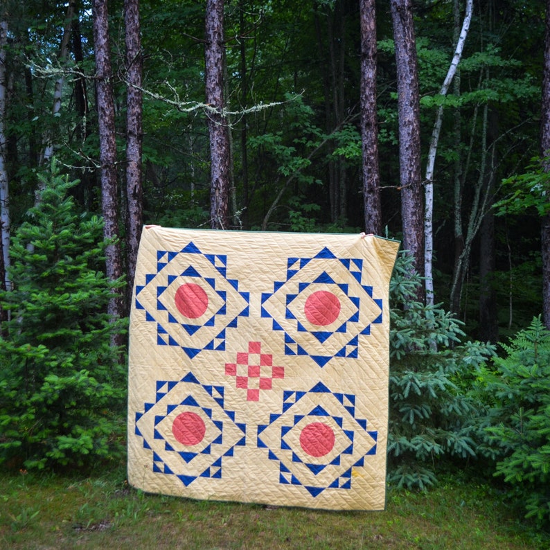 Yellow quilt with blue triangles and salmon colored circles and squares.