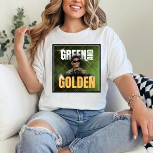 May include: White t-shirt with a green and gold graphic featuring a man wearing a green suit and a gold bow tie. The graphic says "Green and Golden".