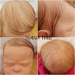 May include: Close-up of a baby doll's head with sparse, brown hair. The doll's eyes are closed and the hair is parted on the side.