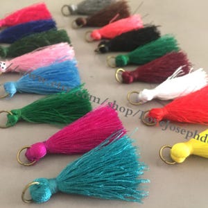 Può includere: Assortimento di frange colorate con anelli dorati. Le frange sono realizzate in filato morbido e soffice e sono disponibili in una varietà di colori, tra cui rosso, blu, verde, rosa, bianco, giallo e viola.