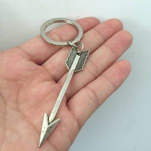 Op de afbeelding: Zilveren pijl sleutelhanger met een sleutelring. De pijl heeft een gedetailleerd ontwerp en een puntige punt.