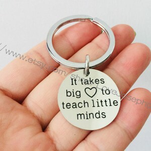 May include: Silver keychain with a heart and the text "It takes big heart to teach little minds".