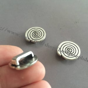 May include: Three silver metal charms with a spiral design. The charms are about 1 inch in diameter.