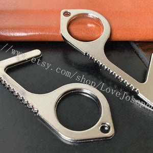 May include: Two silver-toned door openers with a textured handle and a loop for attaching to a keychain. One opener has a serrated edge and the other has a smooth edge.