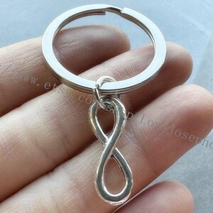 Op de afbeelding: Zilveren sleutelhanger met een oneindigheidssymbool. Het oneindigheidssymbool is bevestigd aan een zilveren sleutelring.