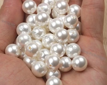 May include: A pile of white pearl beads, approximately 20mm in diameter, with a hole in the centre of each bead.