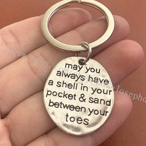 May include: Silver keychain with a round charm that reads "may you always have a shell in your pocket & sand between your toes".
