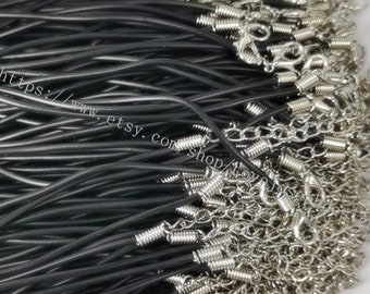 May include: Close-up of a collection of black cord necklaces with silver-colored clasps and chain extensions. The cords are tightly bundled together, with the clasps and chains visible at the top. The image has a neutral background.