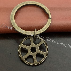 May include: A bronze key chain with a gear charm. The gear has a detailed design with six spokes and a central hub.