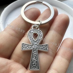 May include: Silver Ankh key chain with intricate details. The Ankh is a symbol of life and eternal life in ancient Egyptian religion.