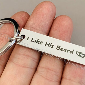 May include: Silver keyring with a rectangular tag that reads "I Like His Beard" with two interlocking hearts.