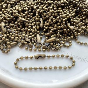 May include: A pile of brass ball chain with a single chain separated for display. The chain is made of small, round, brass beads.