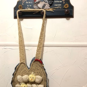 May include: A crochet egg gathering bag with a denim base, in tan and cream. The bag has egg pockets and two yellow chick embellishments. It hangs below a wooden sign that reads "Chicken House".