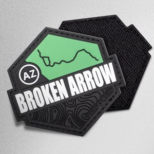May include: A black and green patch with the words "BROKEN ARROW" in white. The patch has a green hexagon with a black line drawing and the letters "AZ" in a white circle. The bottom of the patch has a topographic design.