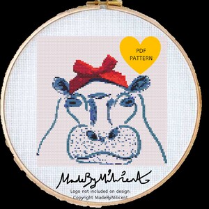 May include: Cross stitch pattern of a blue hippo wearing a red bow. The pattern is in a hoop and the text "PDF PATTERN" is in a yellow heart shape.