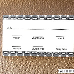 May include: A white card with a black border and a black and white patterned design. The card has a section for the name of a dish and check boxes for vegan, vegetarian, meat, has nuts, gluten-free, and dairy-free.
