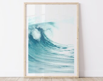 May include: A framed photograph of a large, blue ocean wave crashing against the shore. The wave is captured in a moment of motion, with white foam and spray.
