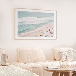 May include: An aerial photograph of a beach with turquoise water and white sand.  People are relaxing on the beach under colorful umbrellas.