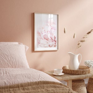 Pu&ograve; includere: Una stampa incorniciata di un primo piano di un fiore di peonia rosa. La stampa &egrave; appesa a una parete rosa chiaro in una camera da letto.