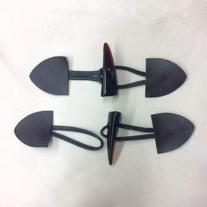 Pode incluir: Dois conjuntos de botões de couro preto com tiras elásticas pretas e botões de chifre castanho escuro.