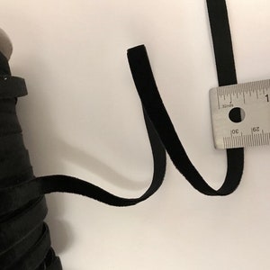 Pu&ograve; includere: Nastro di velluto nero misurato con un righello. Il nastro &egrave; largo circa 2,5 cm.