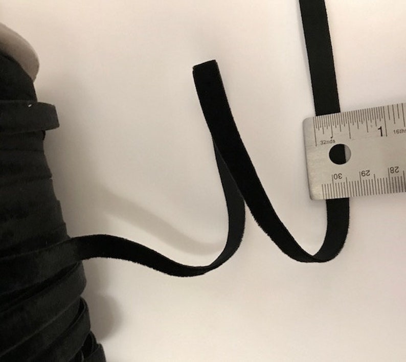 Pu&ograve; includere: Nastro di velluto nero misurato con un righello. Il nastro &egrave; largo circa 2,5 cm.
