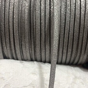 May include: A spool of silver glitter cord, a type of decorative trim, with a close-up of a single strand.