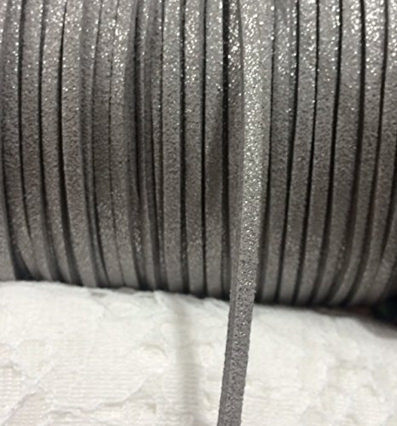 May include: A spool of silver glitter cord, a type of decorative trim, with a close-up of a single strand.