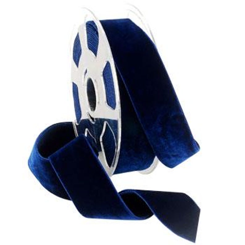 Puede incluir: Un carrete de cinta de terciopelo azul oscuro. La cinta tiene 2,5 cm de ancho y est&aacute; enrollada alrededor de un carrete de metal plateado.