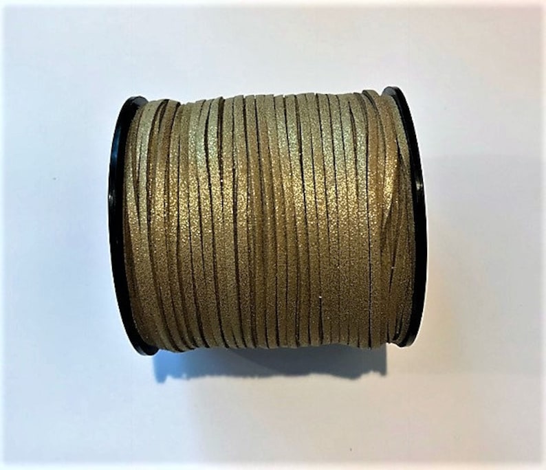 May include: A spool of gold-colored cord with a black plastic bobbin. The cord is made of a soft, pliable material and has a subtle shimmer.