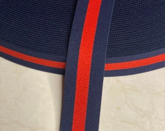 May include: Navy blue elastic trim with a thick red stripe down the center. The trim is folded in half, showing the red stripe on both sides.