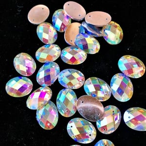 Puede incluir: Una colección de piedras de cristal ovaladas iridiscentes con un diseño facetado. Las piedras de cristal tienen un efecto arcoíris y son perfectas para manualidades y embellecer proyectos.