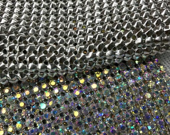 May include: Two sheets of silver and iridescent rhinestone fabric. The top sheet has a raised, textured pattern. The bottom sheet has a flat, smooth surface.