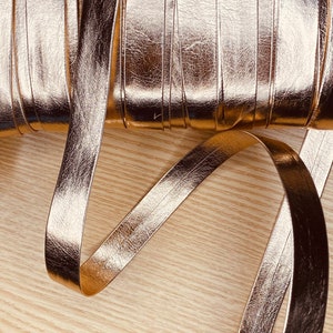 May include: A roll of metallic gold faux leather ribbon. The ribbon is approximately 1 inch wide and has a textured surface.