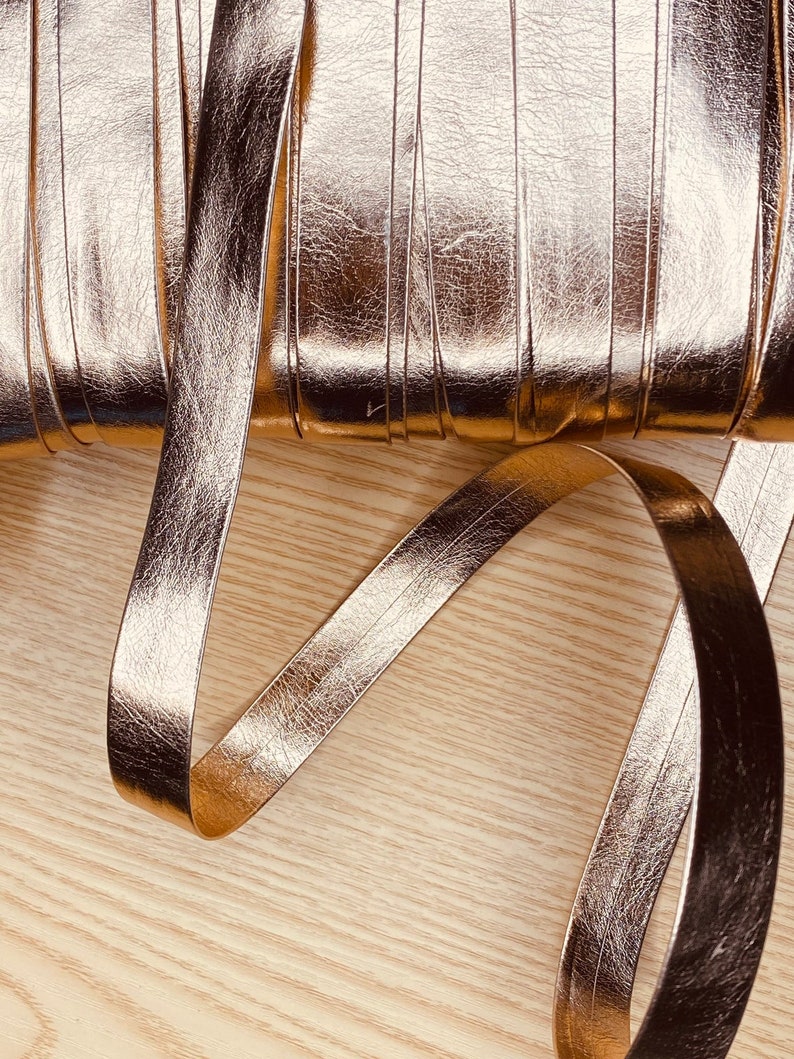 May include: A roll of metallic gold faux leather ribbon. The ribbon is approximately 1 inch wide and has a textured surface.