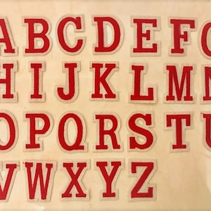 May include: A set of 26 iron-on letters in a white outline with red fill. The letters are in uppercase and are arranged in alphabetical order.