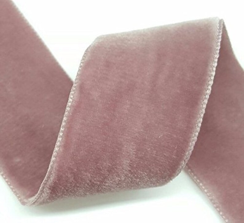 Puede incluir: Un rollo de cinta de terciopelo rosa polvoriento. La cinta es suave y tiene un brillo sutil.