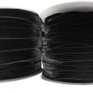 May include: Two spools of black velvet ribbon, each wound around a cardboard core. The ribbon is smooth and has a subtle sheen.