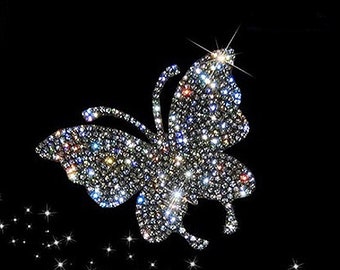 May include: A sparkling silver butterfly made of rhinestones on a black background.