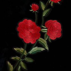 May include: Red embroidered roses with green leaves on a black background.