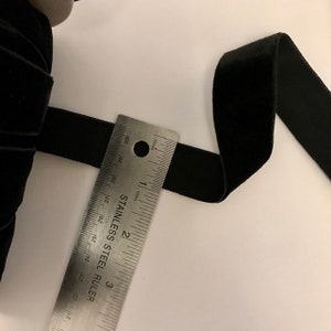 Pu&ograve; includere: Nastro di velluto nero misurato con un righello, che mostra una larghezza di 2,5 cm.